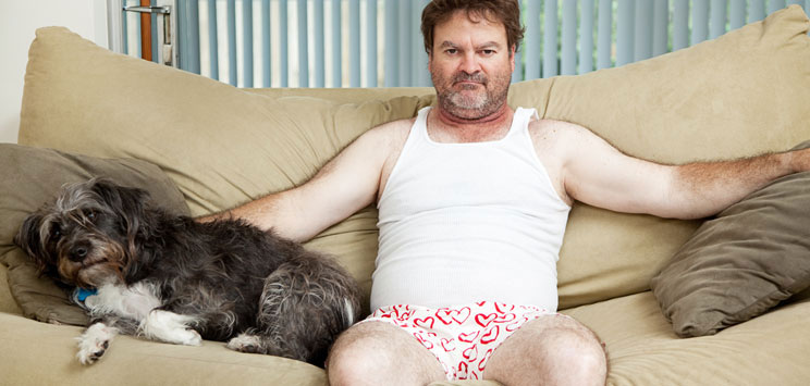 man in underwear with dog on couch