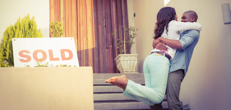 Couple embracing in front of sold home